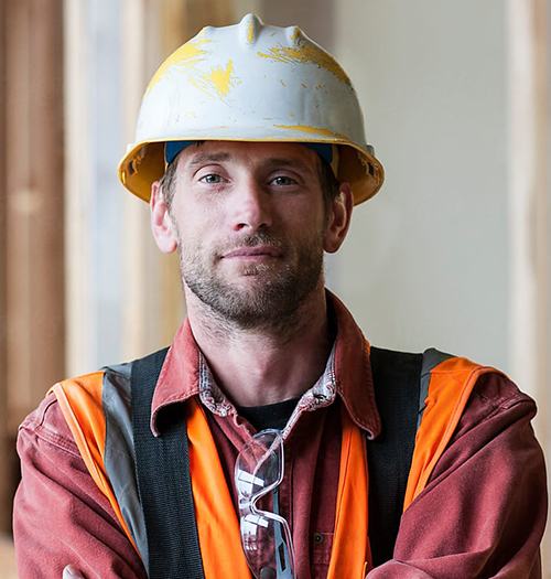 Confident construction worker wearing a safety helmet and vest.