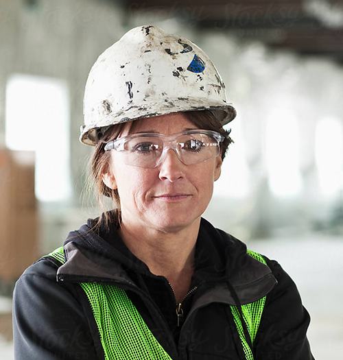 Confident female construction worker in safety gear at a job site.