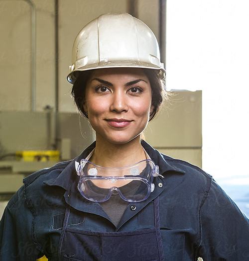 Woman construction worker wearing a white hard hat and safety goggles.