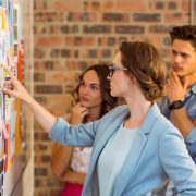 Woman pointing at notes on a board during a collaborative meeting.