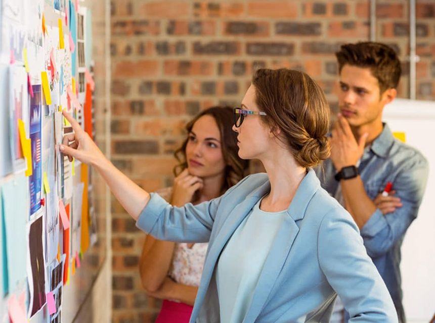 Woman pointing at notes on a board during a collaborative meeting.