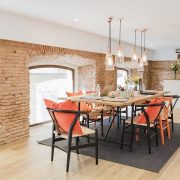 Modern dining area with rustic brick walls and vibrant orange chairs.