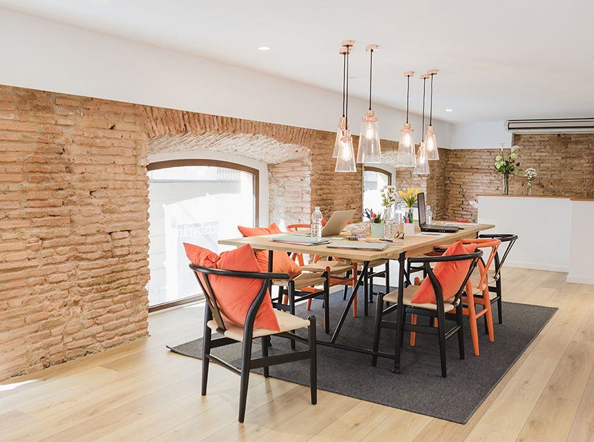 Modern dining area with rustic brick walls and vibrant orange chairs.