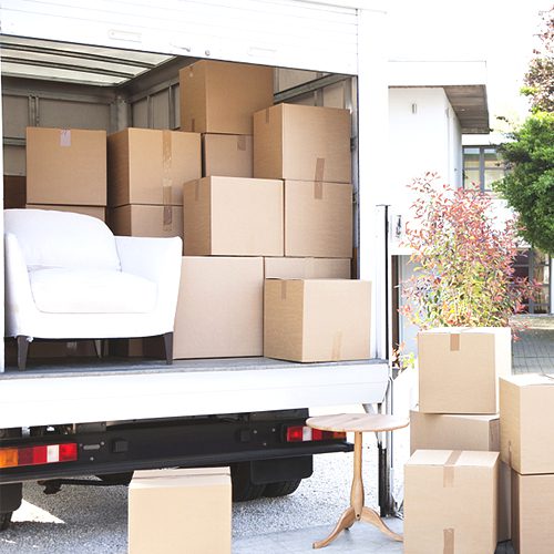 Moving truck loaded with boxes and a white armchair.