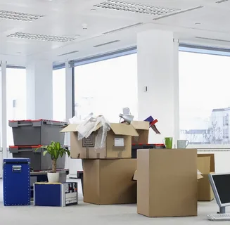 Office space filled with packed moving boxes and scattered items.