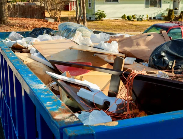 A dumpster filled with various discarded construction materials and debris.