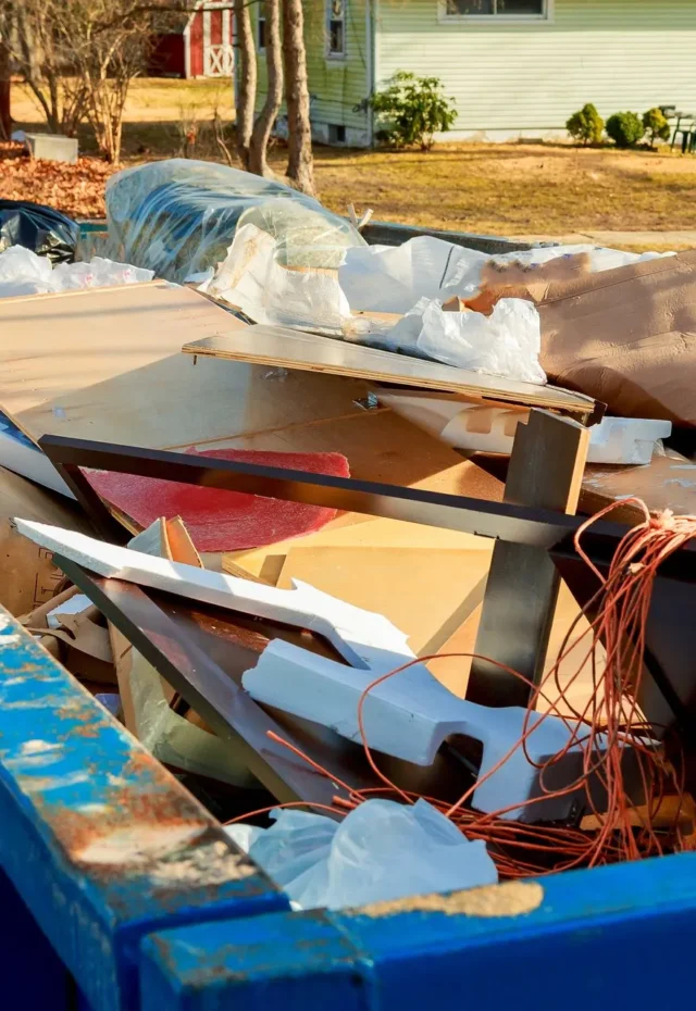 A dumpster filled with various discarded construction materials and debris.